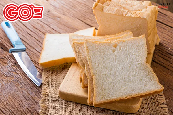 Một ổ bánh mì gối truyền thống được cắt lát đặt trên thớt gỗ, cho thấy kết cấu mềm mịn của bánh