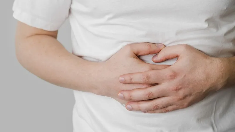 Một người phụ nữ trẻ đang ôm bụng đau, biểu cảm khó chịu - hình ảnh minh họa người bị đau bụng do vấn đề tiêu hóa cần tránh măng