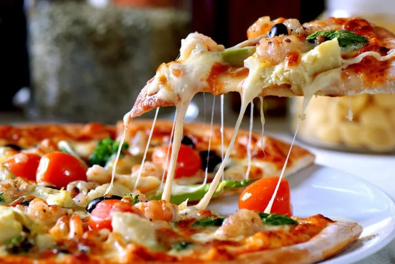 Một người phụ nữ trẻ đang suy nghĩ liệu ăn pizza có tốt cho sức khỏe không