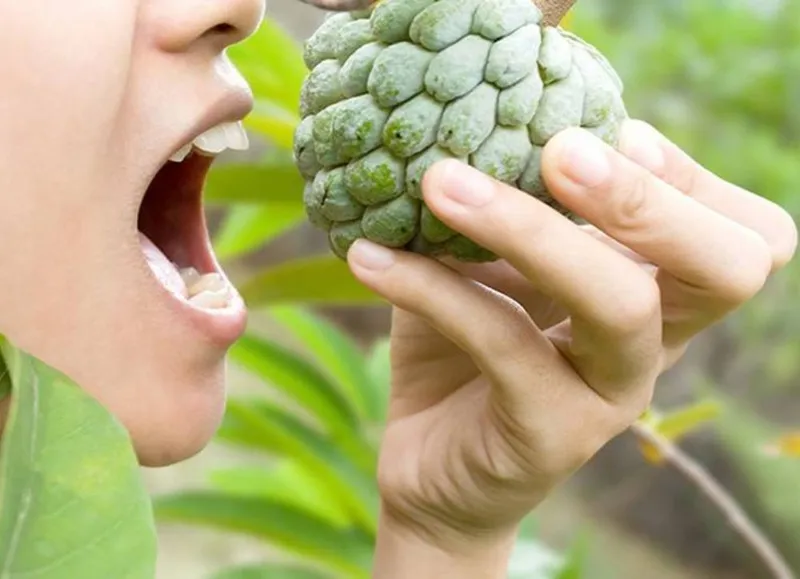 Người phụ nữ vui vẻ thưởng thức na tươi ngon trong nhà bếp