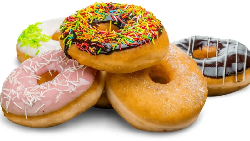 Chiếc bánh donut truyền thống màu vàng ươm, được đặt trên một đĩa gỗ với các nguyên liệu làm bánh xung quanh như bột mì và trứng.