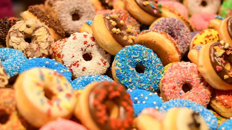 Một người phụ nữ trẻ đang cười tươi và chuẩn bị ăn một chiếc bánh donut phủ sô cô la.