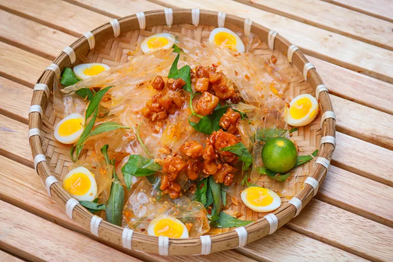Một đĩa bánh tráng nướng đầy màu sắc với trứng, xúc xích và các loại topping hấp dẫn