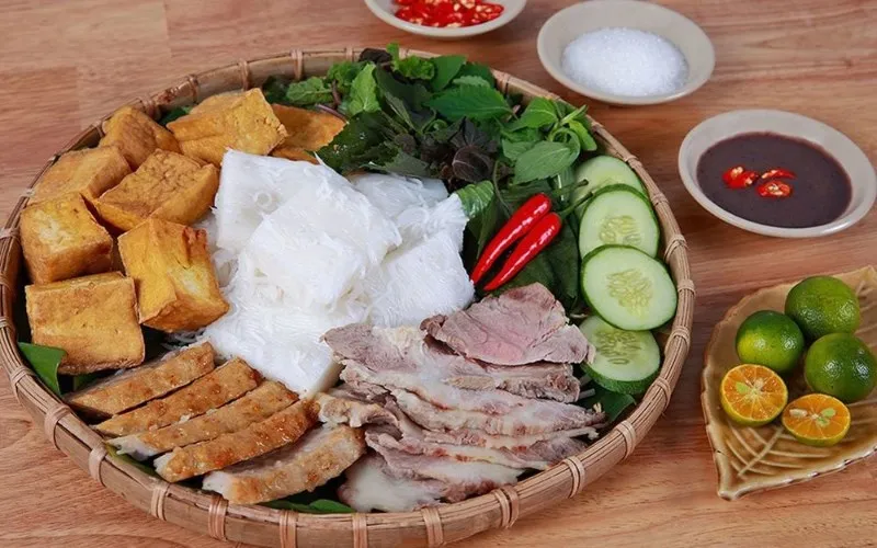 Một người phụ nữ vui vẻ thưởng thức món bún trộn nhiều rau xanh tươi mát