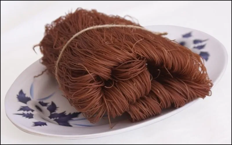 Những sợi bún gạo lứt màu tím than đặc trưng trên đĩa gỗ