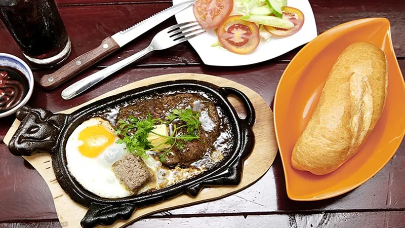 Một phần bò bít tết kiểu Việt Nam với trứng ốp la, khoai tây chiên và salad