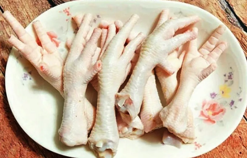 Chân gà đang được luộc trong nồi cùng gừng và sả