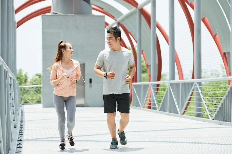 Một người phụ nữ đang chạy bộ trên vỉa hè ven hồ vào buổi sáng sớm