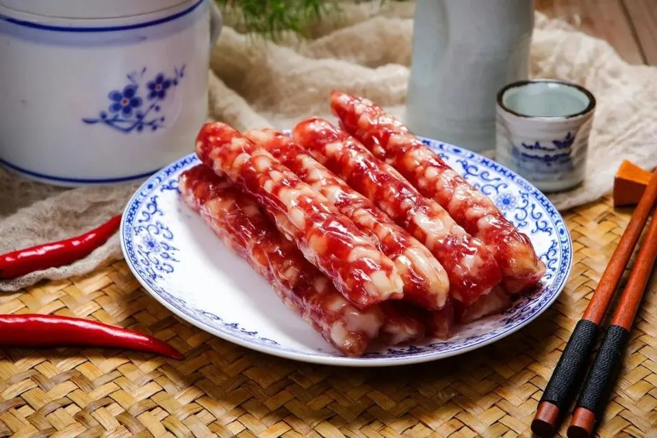 Đĩa lạp xưởng đã thái lát và chiên nhẹ, bày trên đĩa cùng rau thơm