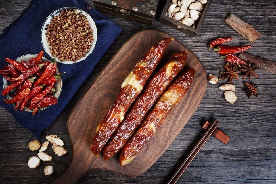 Đĩa lạp xưởng hấp hoặc luộc đã thái lát, ăn kèm với rau xanh và củ quả