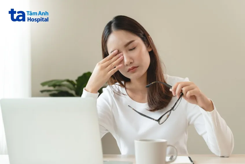 Người phụ nữ đang ôm bụng với vẻ mặt mệt mỏi, do thiếu năng lượng