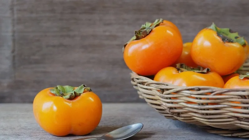 Một quả hồng tươi ngon đặt cạnh vài quả trứng gà, minh họa cho sự kết hợp không nên có trong chế độ ăn uống