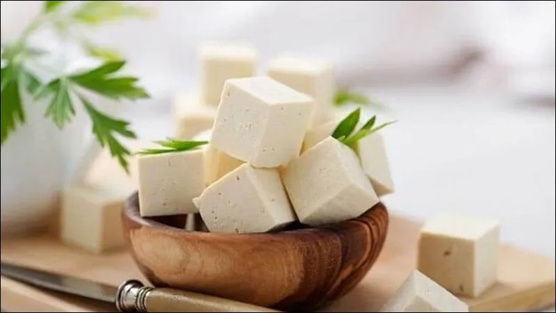 Người phụ nữ tươi cười đang cầm một bát đậu phụ trộn salad rau xanh tươi mát